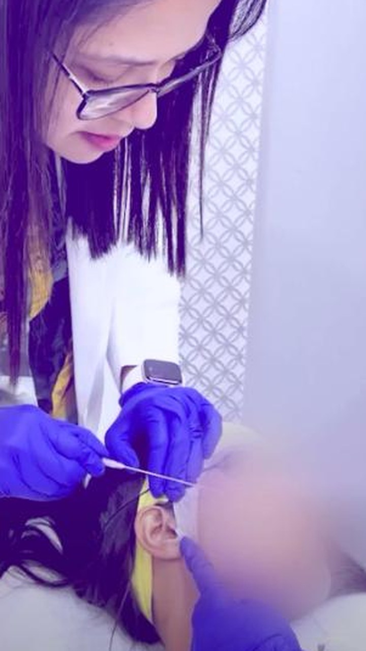 Dr. Sifat-E-Aman, gloved, carrying out a thread procedure along a patient's jawline.